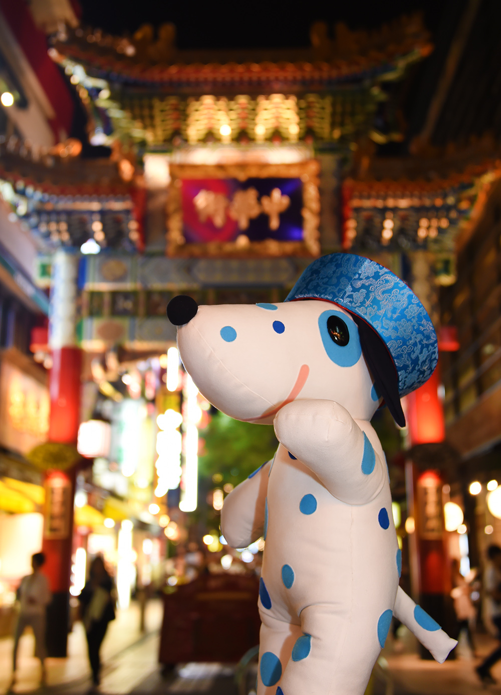 夜のネオンがきらめく横浜中華街の門の前で中華帽をかぶって記念撮影するブルーダル